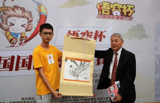日本手塚制作株式会社社长松谷孝征向“悟空杯·手塚奖”获奖者黄明宇赠送画稿。（主办方供图）
