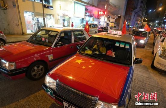 资料图：8月23日晚，“守护香港大联盟”联同香港的士司机从业员总会发起“守护香港·风雨同舟”大行动，在港岛筲箕湾中心，有超过140多辆出租车车身贴着海报，车尾悬挂五星红旗依次有序驶向主干道，呼吁社会反对暴力。/p中新社记者 张炜 摄