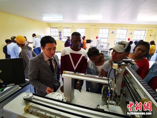 鲁班工坊任教老师裴志坚为南非院校师生介绍机电一体化实训设备。