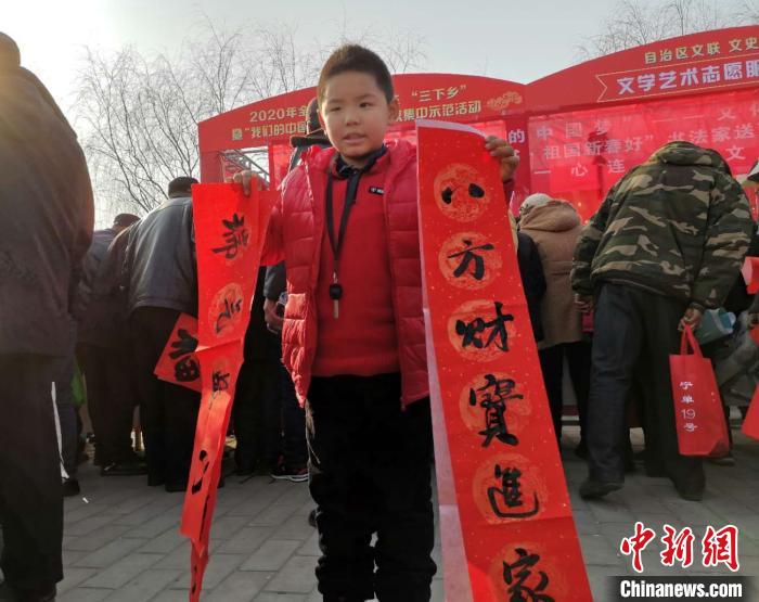 小朋友展示书法家协会成员为其写的春节对联。　李海龙 摄