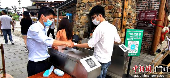 5月2日，在梦呜苗寨，游客们按照1.5米的距离排队测量体温。