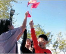 讲老故事说童年趣事 老少三代高举红旗环湖走