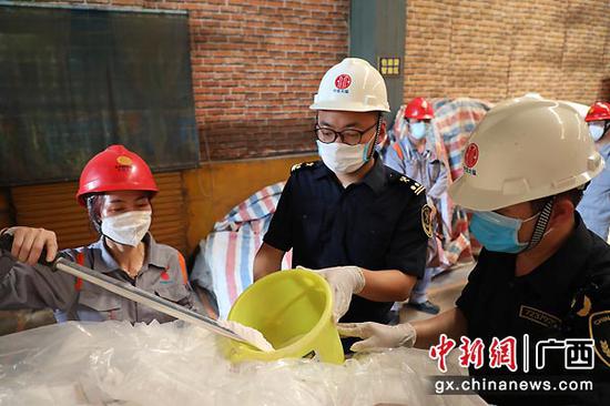 图为工作人员对即将出口的锰矿产品进行取样。