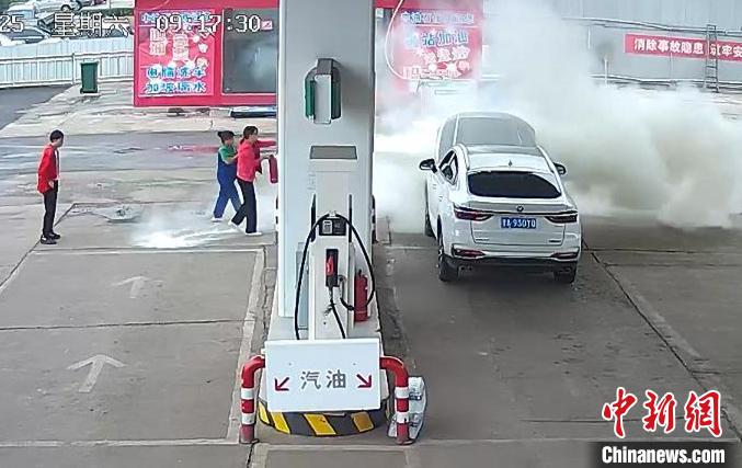 加油员和车主正在对汽车发动机部位明火进行扑救。　视频截图 摄