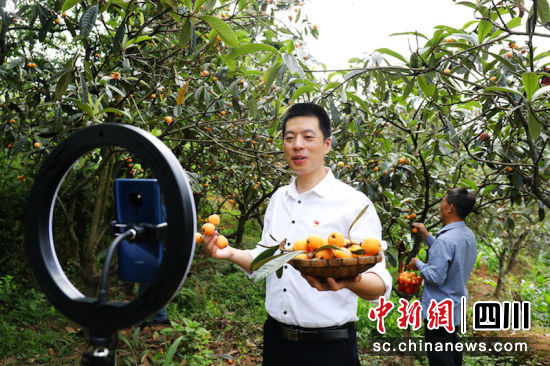 第一书记夏彬翰正通过手机直播平台向网友推销当地的特色农产品。杨尚威 摄
